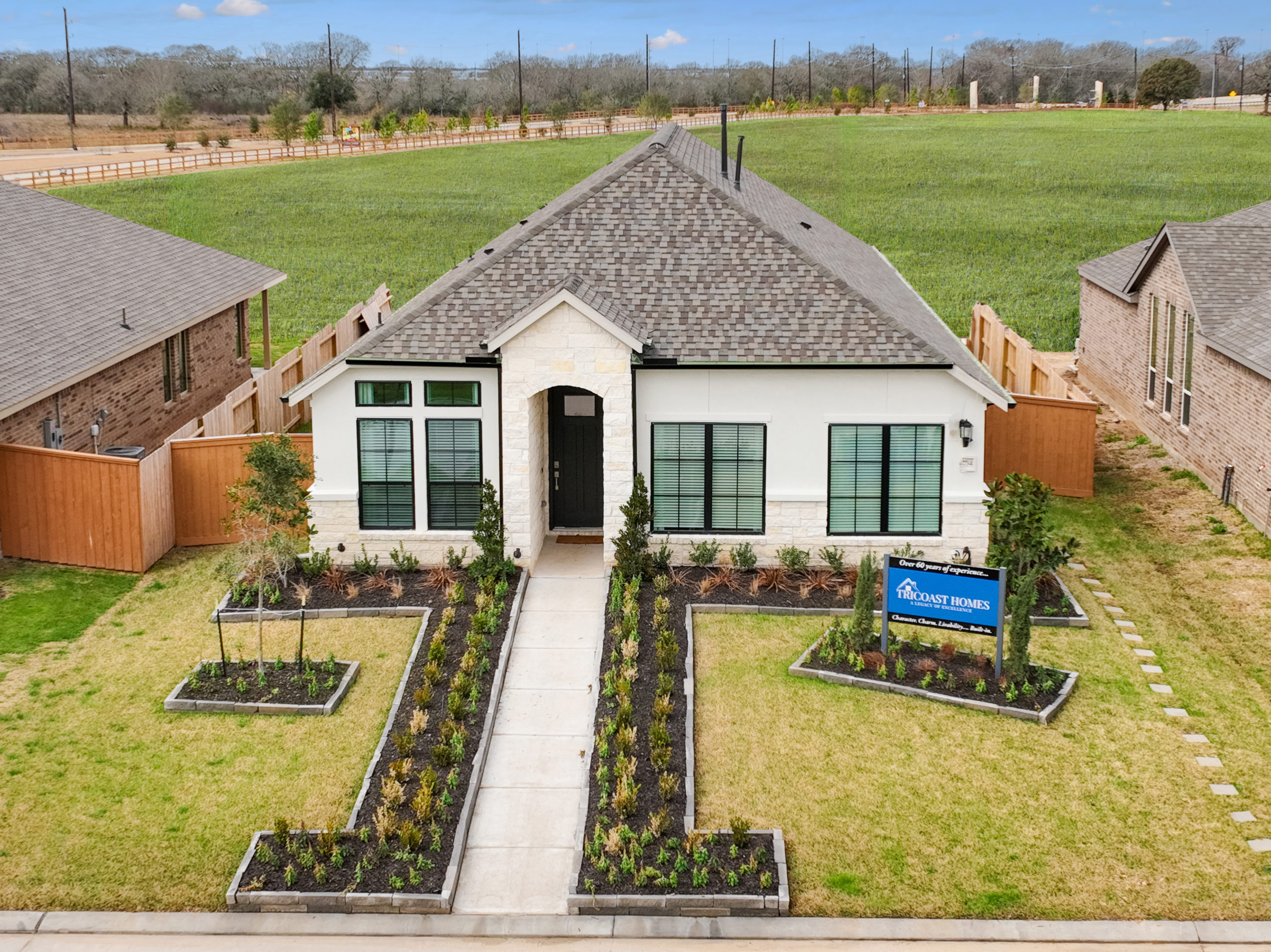 Single-story house with a landscaped front yard and a "Perry Homes" sign. The house features a gabled roof, light-colored exterior, and large windows. Located in a master planned community near Richmond, a concrete path leads to the front entrance.