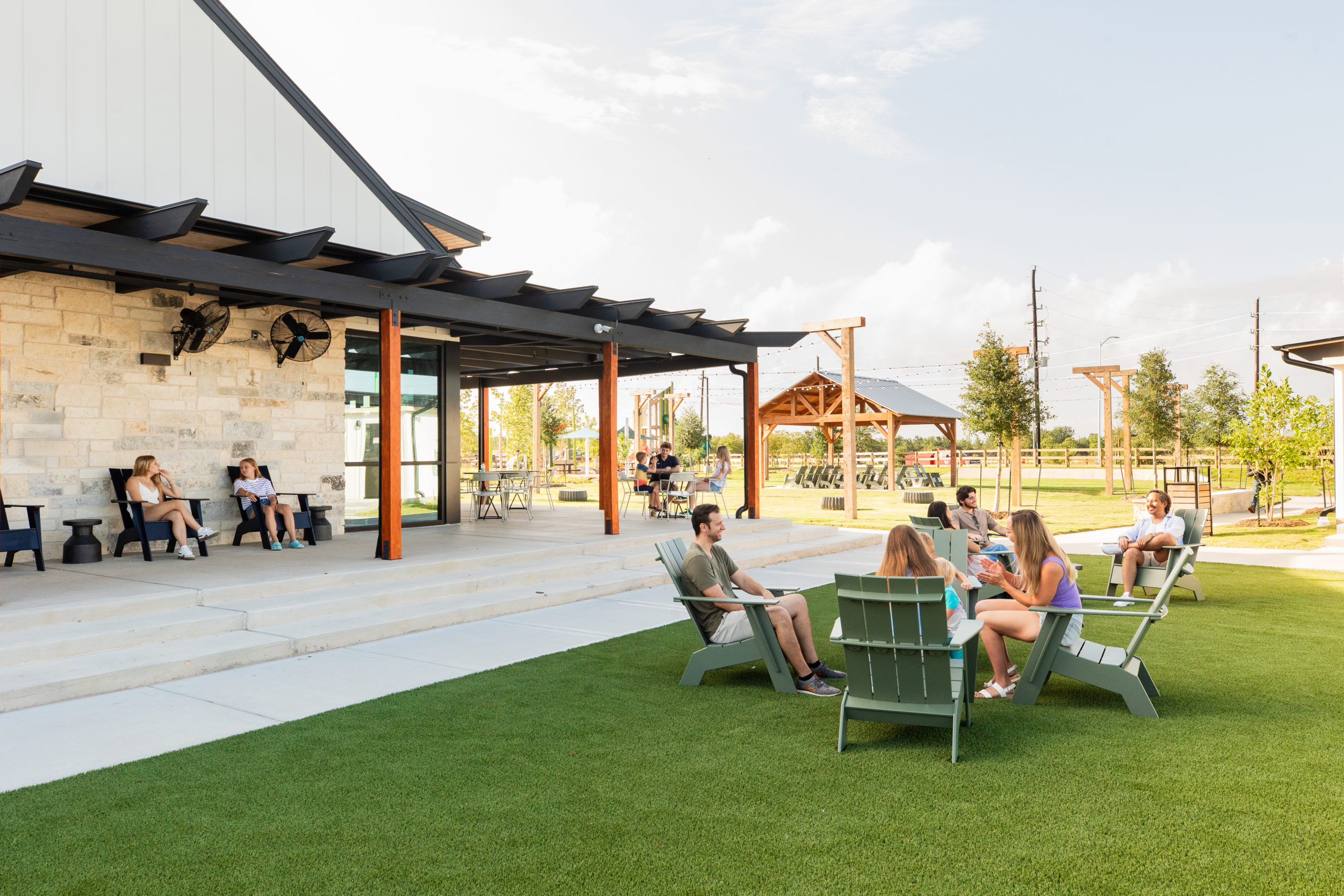 A playground near Richmond with various climbing structures, slides, and shaded areas, surrounded by greenery and picnic tables under a partly cloudy sky. The charming spot is a favorite for families in Fort Bend County, perfect for an afternoon of fun.