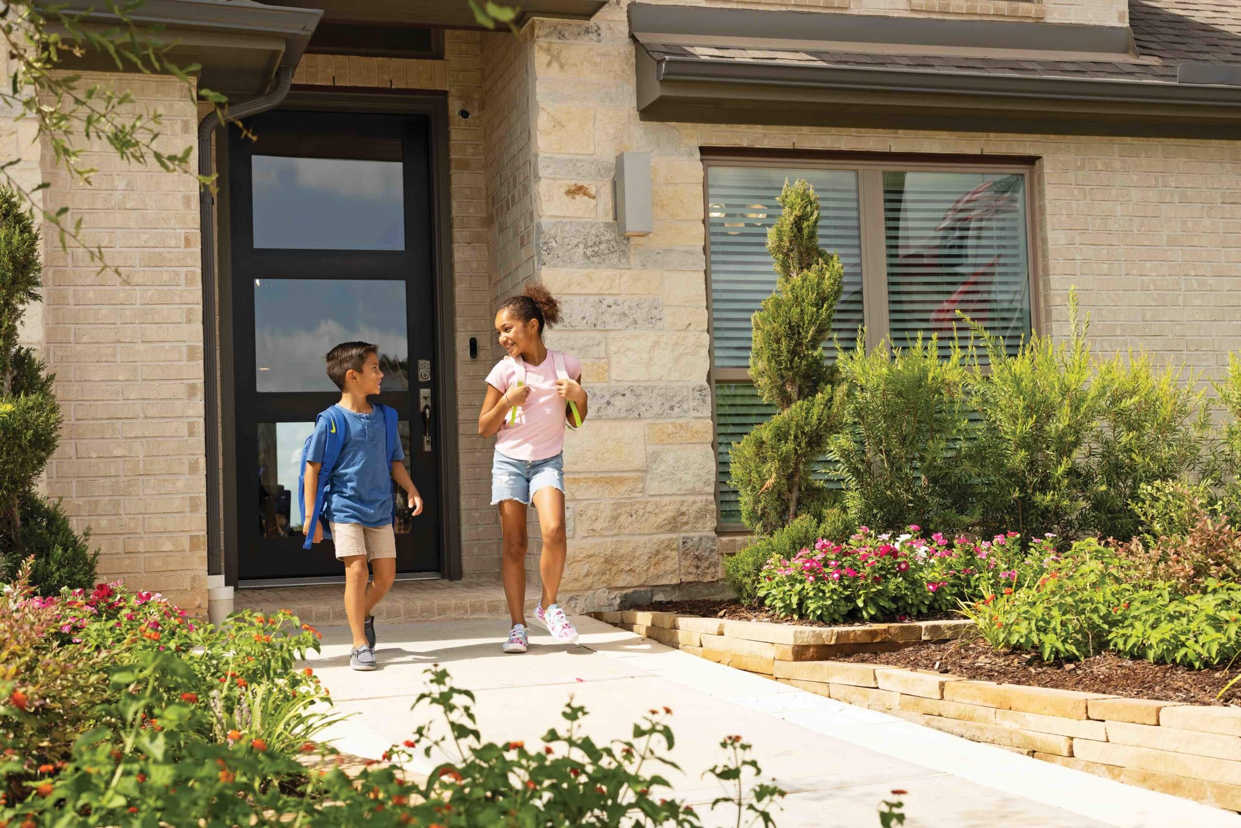 In a master-planned community near Rosenberg, a diverse group of five children in a classroom gathers around a tablet, engaged in a STEM activity with various electronic components and robotic parts spread across the table.